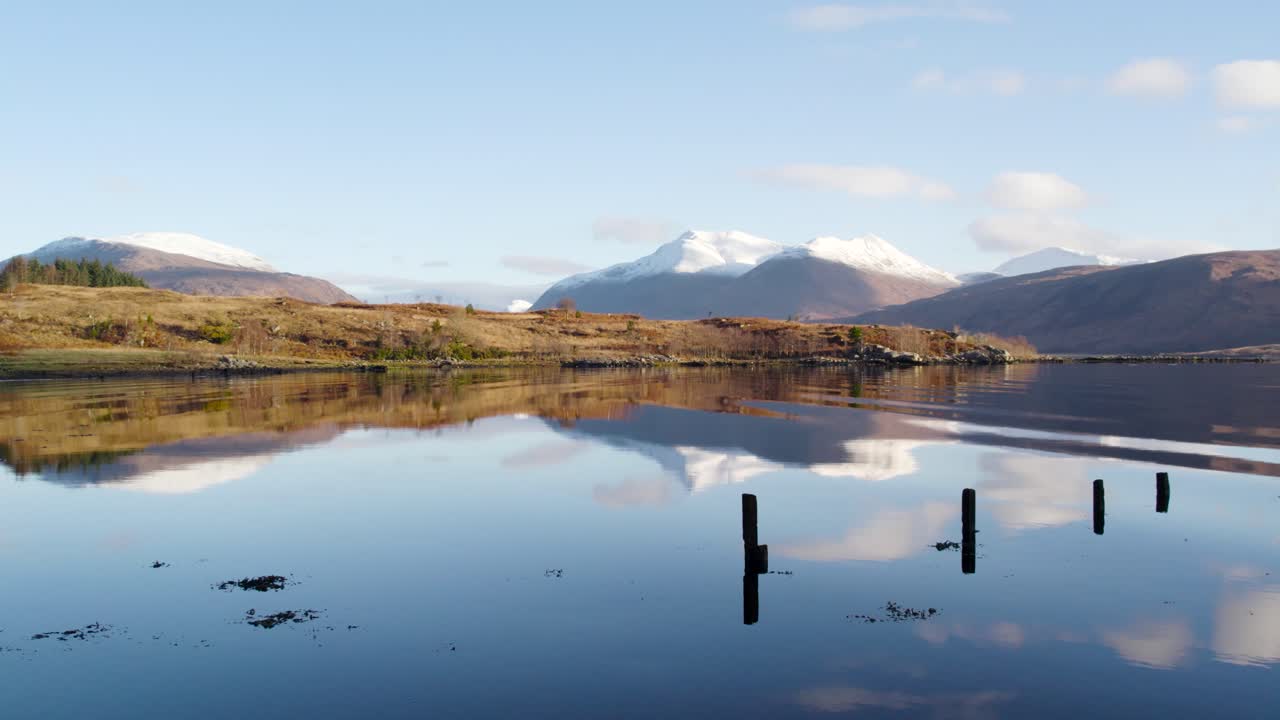 imágenes aéreas de drones que vuelan cerca sobre suaves ondas en el agua de loch etive en glen etive en las tierras altas de escocia con montañas cubiertas de nieve en el fondo y hermosas aguas reflectantes