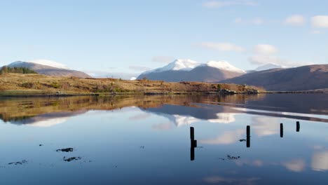 aerial drone footage flying close over gentle ripples in the water of loch etive in glen etive in the highlands of scotland with snow-capped mountains in the background and beautiful reflective water