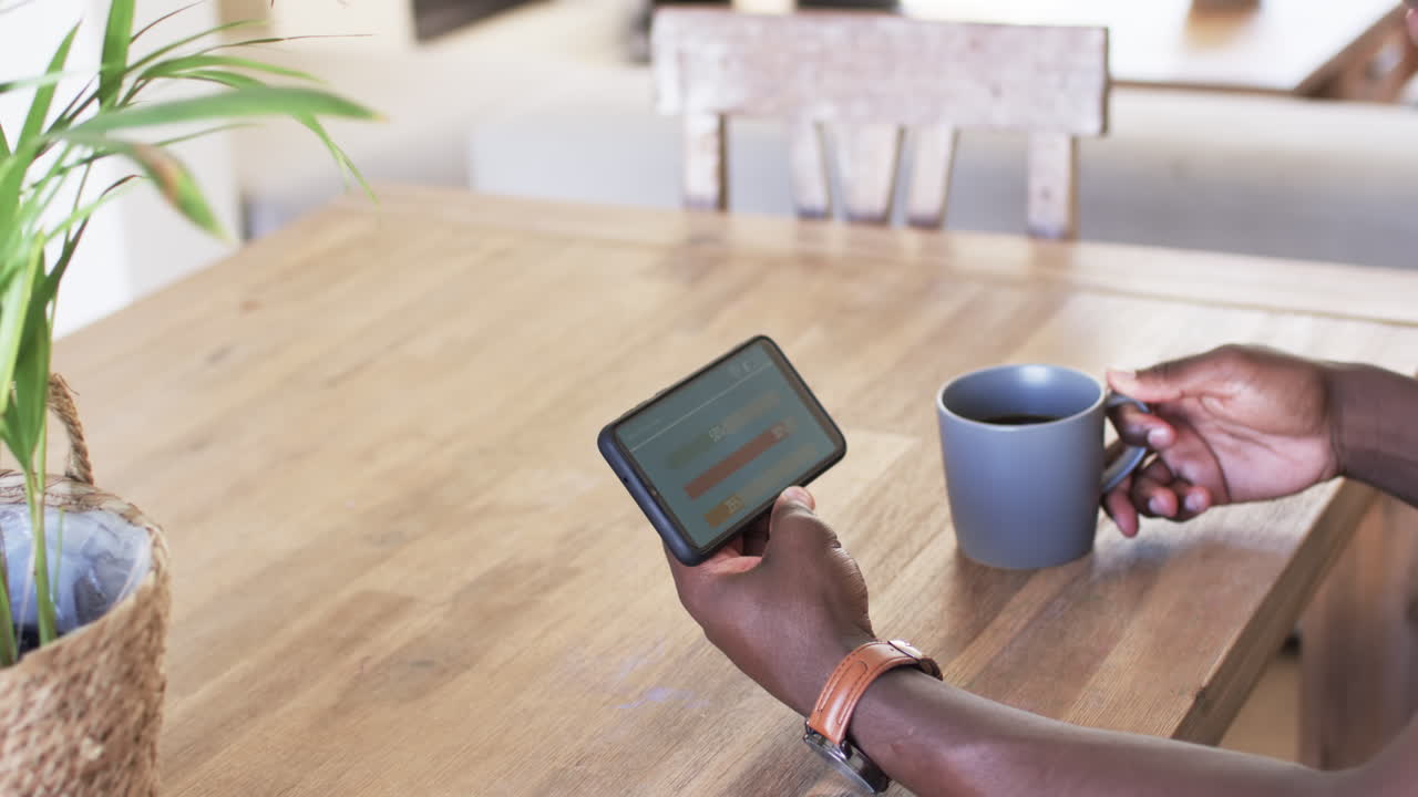 African American man, holding smartphone, checking smart home app energy usage