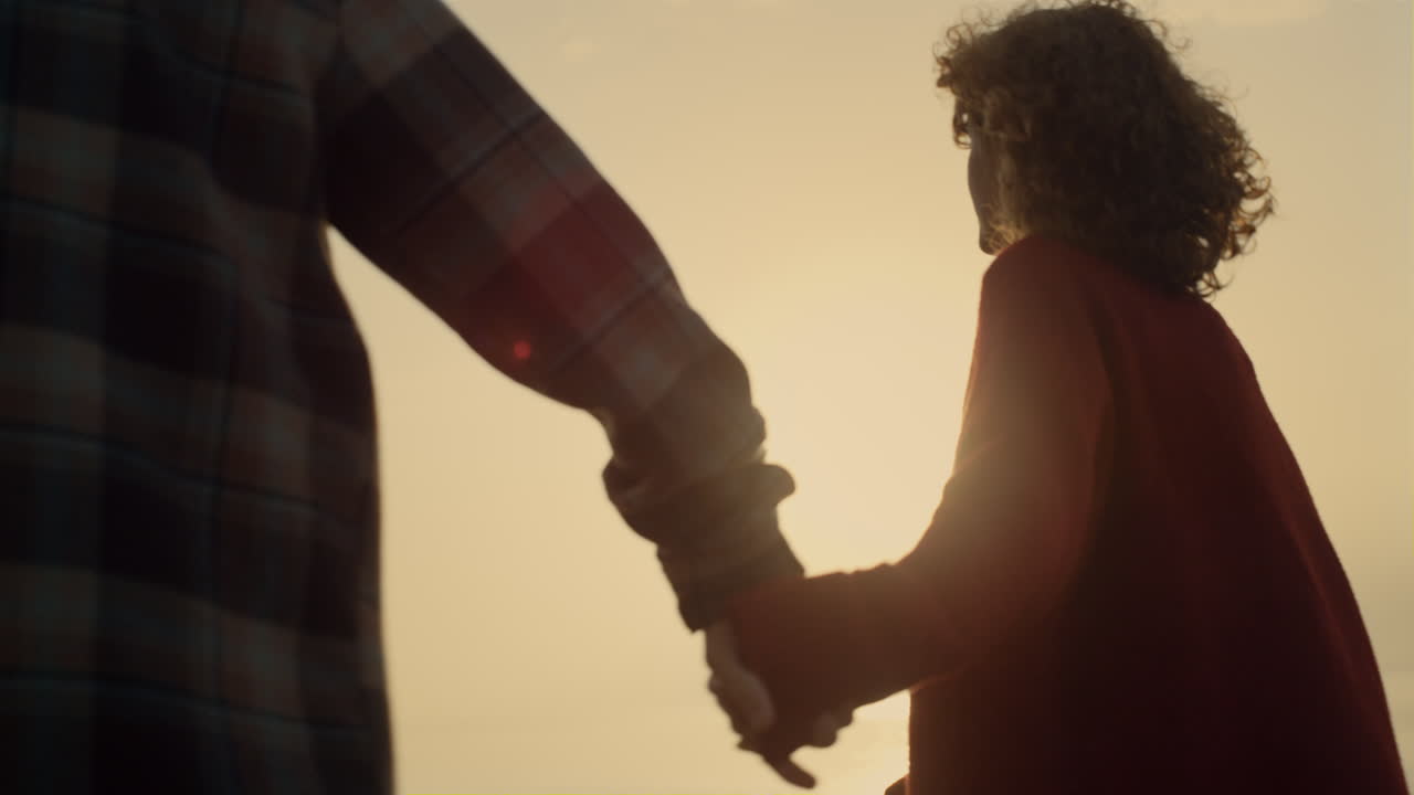 una pareja romántica saliendo en la playa al amanecer. una mujer y un hombre amorosos tomados de la mano.