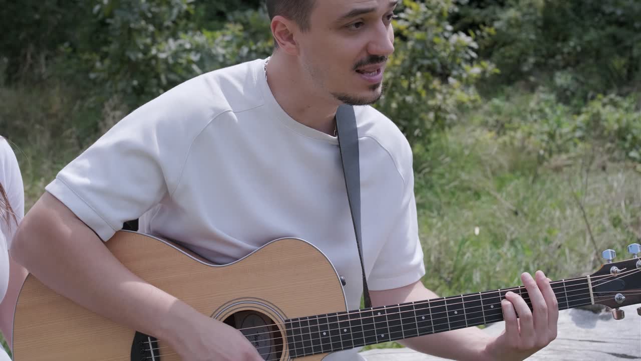 야외에서 어쿠스틱 기타를 연주하는 남자