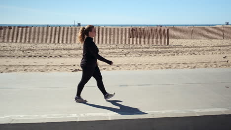 young happy woman taking a walk on the pathway of beach santa monica california