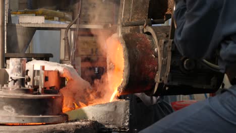 workers pouring smoking melted metal at factory - close-up