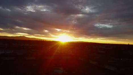 Rayos-De-Sol-A-Través-De-Las-Nubes-Sobre-El-Paisaje-Urbano,-Disparo-De-Drones