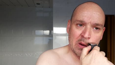 male shaves with an electric razor