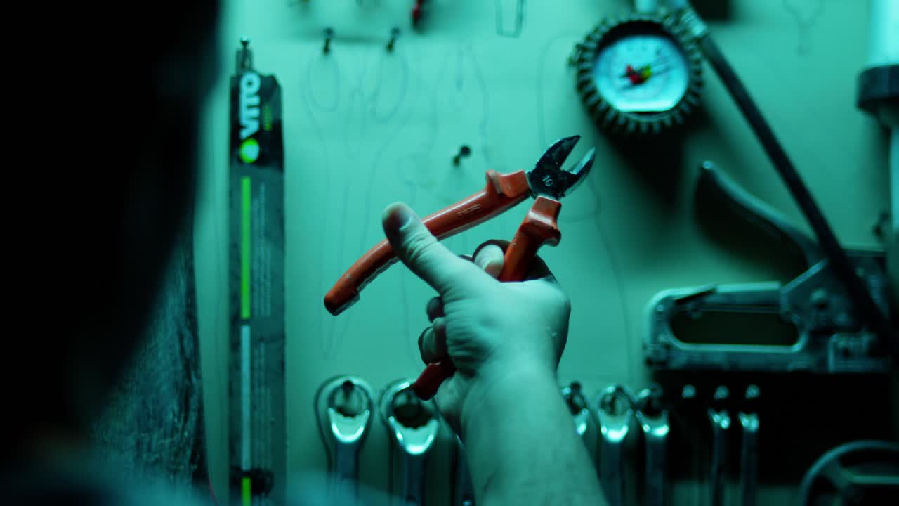 primer plano enfocado de un hombre examinando una herramienta de mano en un taller.