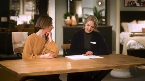 two women sit and compare offers sales associate and customer in store