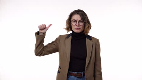 Young-caucasian-woman-wearing-black-blazer-and-brown-jacket-strictly-gesturing-with-thumb-up-YES,-then-showing-hands-shape-meaning-denial-saying-NO-then-smiling-and-over-again.-Standing-over-white-background-at-studio