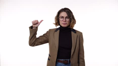 young caucasian woman wearing black blazer and brown jacket strictly gesturing with thumb up yes, then showing hands shape meaning denial saying no then smiling and over again. standing over white background at studio