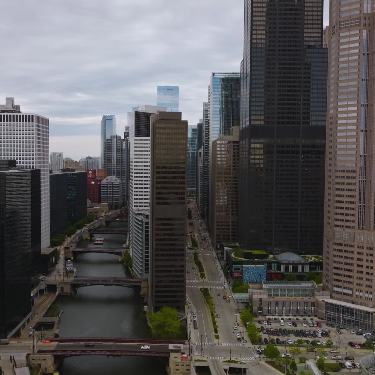 Approaching the row of high buildings separating Chicago River from wide busy multi-lane roads. Beautiful architecture of the city on cloudy day