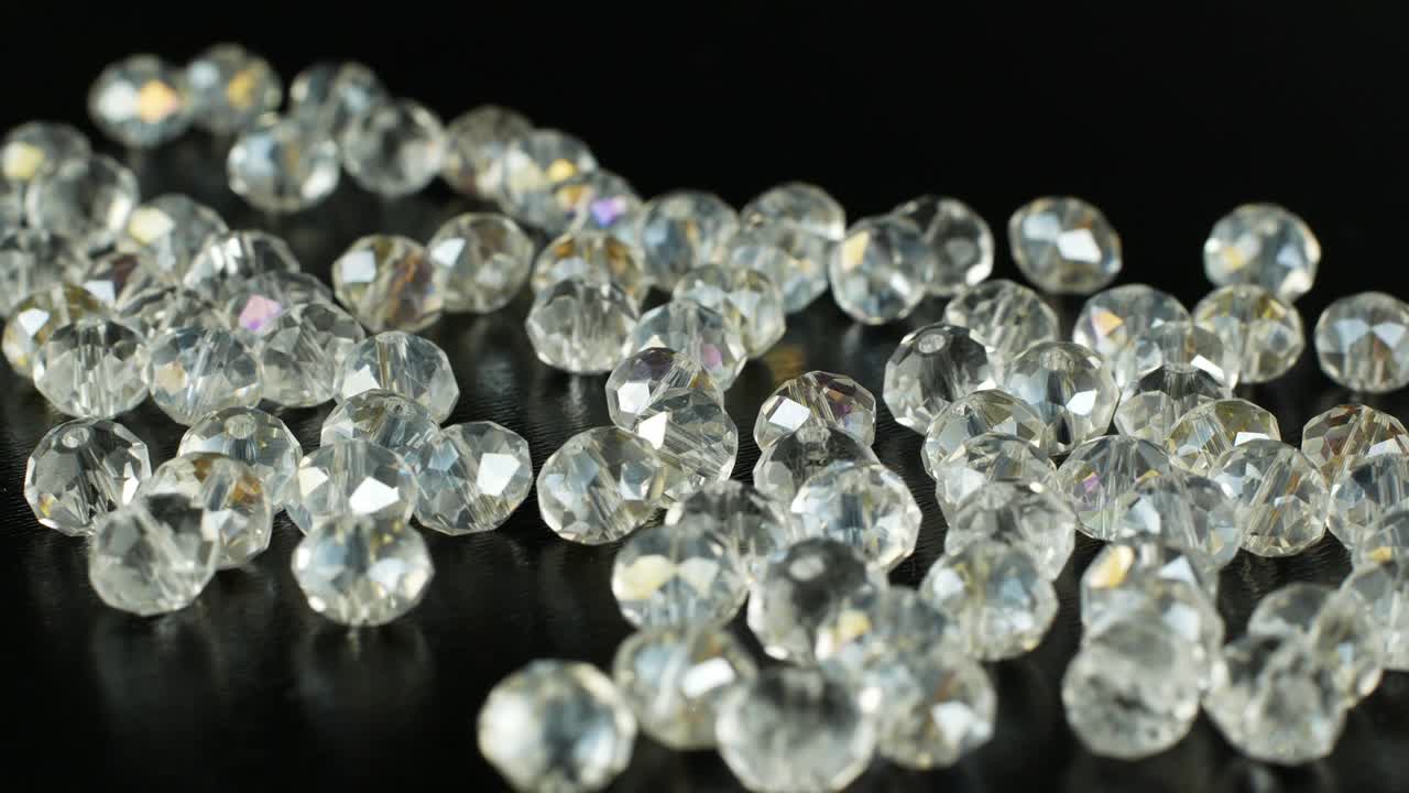 흑색 표면에 보석을 만들고 회전하기위한 색 구슬: 보석을위한 이리데센트 돌의 4k 비디오 클로즈업.