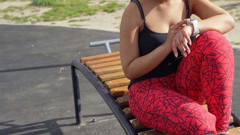 mujer discapacitada usando un reloj inteligente en el parque en un día soleado 4k