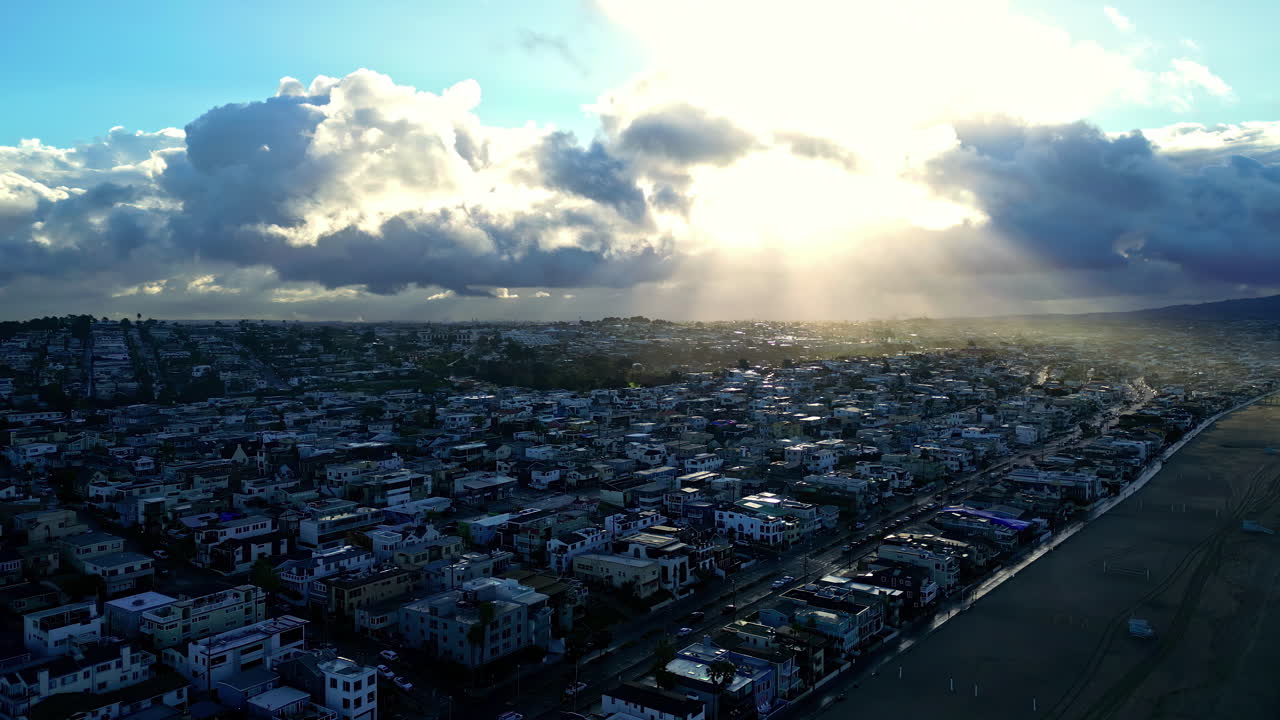 Sunlight breaks through clouds over Manhattan Beach and coastal homes