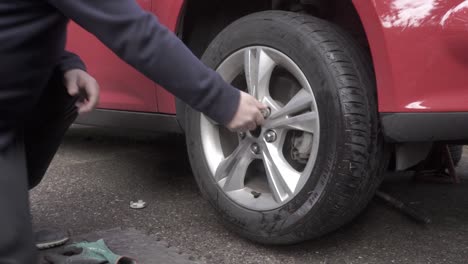 loosening the lug nuts by hand on an automobile