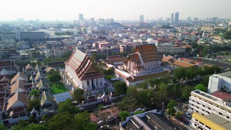 aerial orbit clockwise of wat suthat temple in bangkok, red roof, golden decorations, and spacious temple grounds