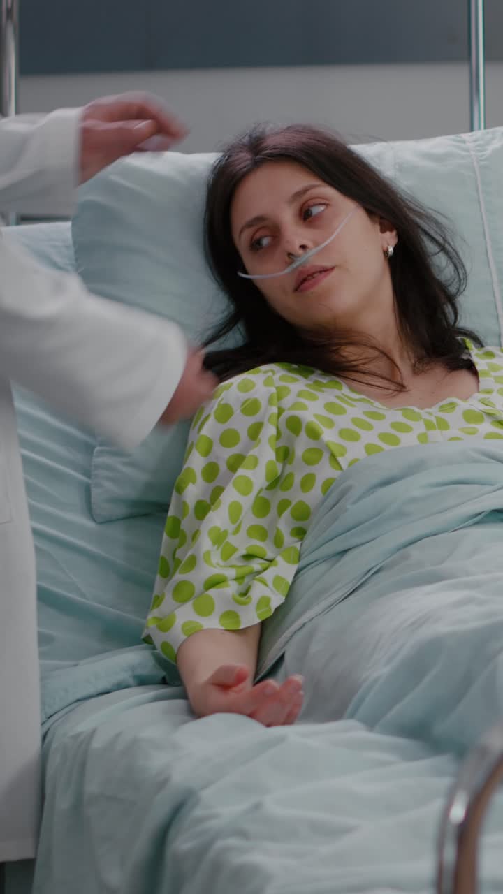 Video verticale: team medico che controlla il battito cardiaco di una donna malata durante l'assistenza respiratoria