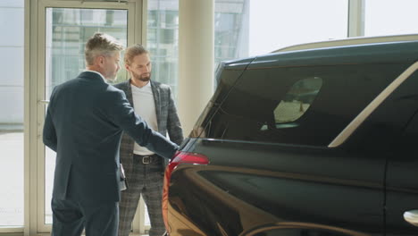 hombres de negocios discutiendo la compra de automóviles en la sala de exposiciones