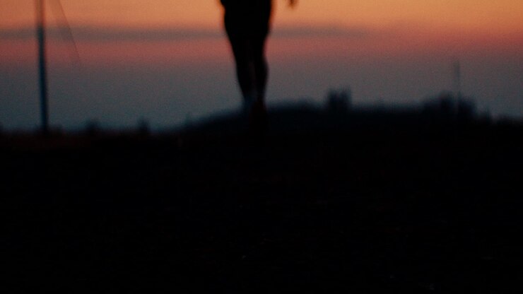 Silhouette of a Person Running/Standing at Sunset near Windmills