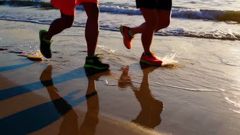 two people running on a beach at sunset or sunrise