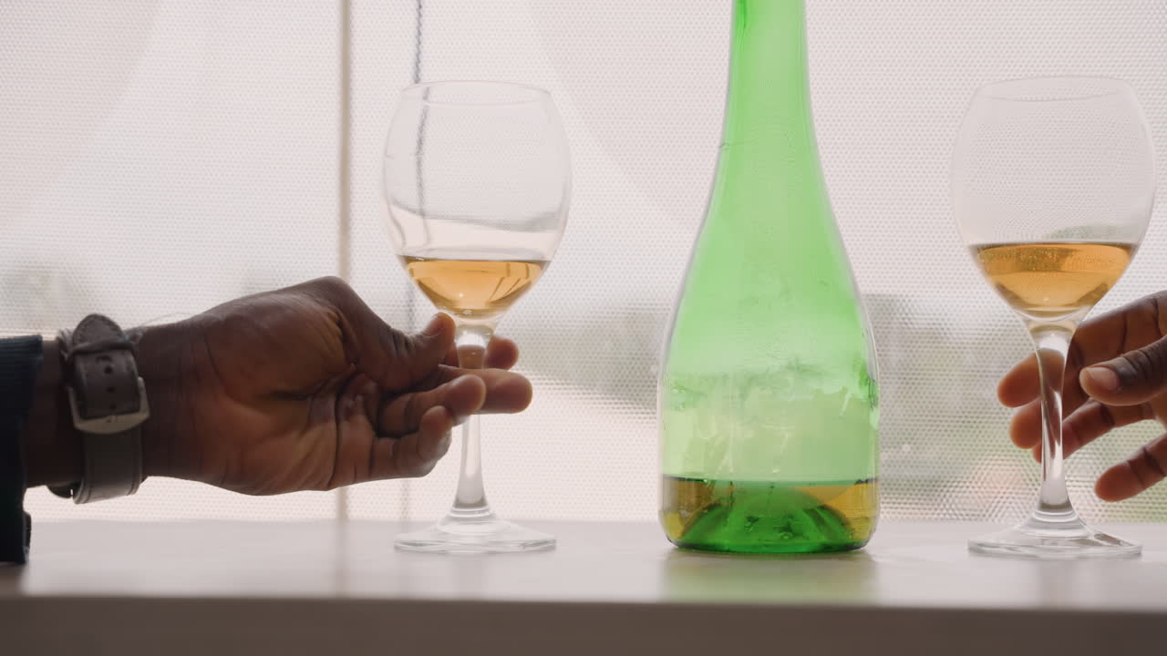Scène urbaine romantique. Verre de vin près d'une fenêtre de ville. Moment intime montrant un homme tendant la main vers une boisson. Cadre romantique et tendre avec des boissons devant les lumières de la ville et la condensation de la fenêtre.
