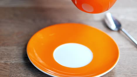 orange coffee cup and saucer with spoon