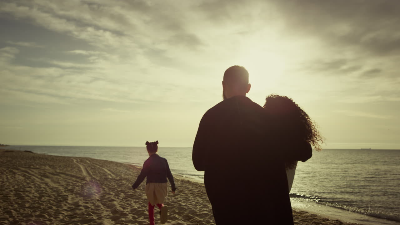 una familia encantadora mirando la playa del ocaso. mamá, papá, hijo caminando por la hermosa costa.