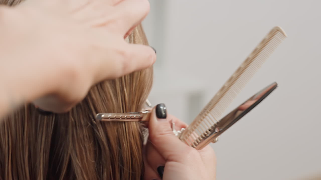 Dettaglio di un parrucchiere che divide i capelli con un pettine e delle clip per fare dei colpi di sole, posizionamento della carta stagnola e preparazione del colore, tecnico che liscia le ciocche, atmosfera da salone editoriale con luce naturale e trasformazione in corso
