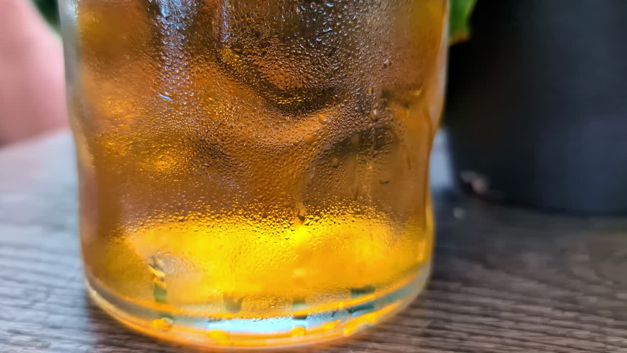 zoom out tiro de un vaso de cerveza con la formación de burbujas que se elevan colocado en una mesa de restaurante