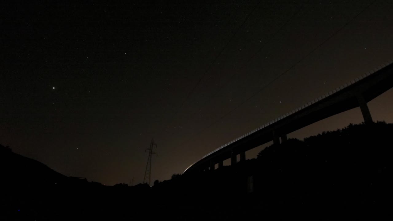 A timelapse form under a bridge. The stars are visible, the camera looks over a construction site,