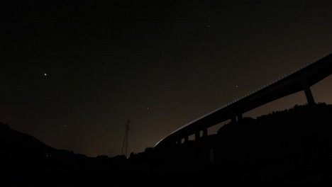 a timelapse form under a bridge. the stars are visible, the camera looks over a construction site,