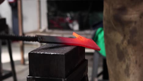 blacksmiths forging hot metal with hammer in workshop