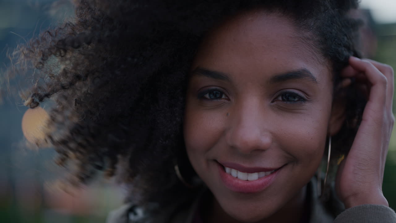 retrato de cerca hermosa joven afroamericana mujer sonriendo corriendo mano a través del cabello mujer negra independiente disfrutando del estilo de vida en la ciudad el viento soplando peinado afro