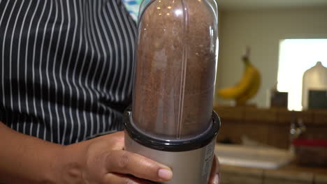 slow motion, woman shaking brown ingredients mixed in blender, closeup