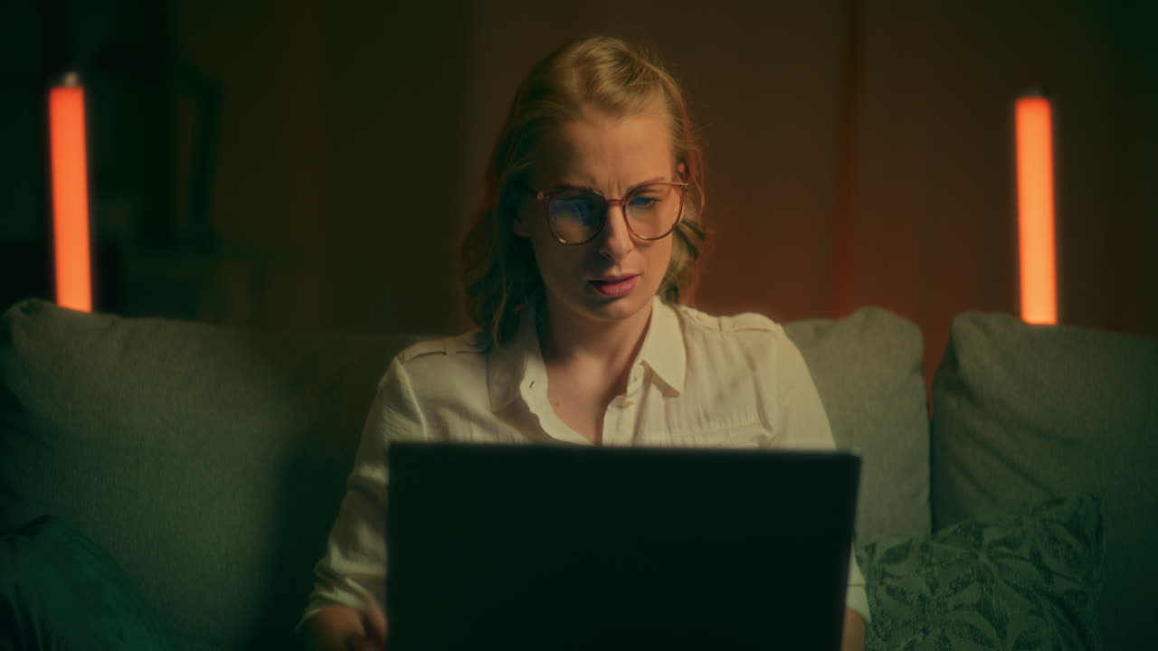 mujer nerviosa se molesta mientras trabaja en la computadora portátil por la noche