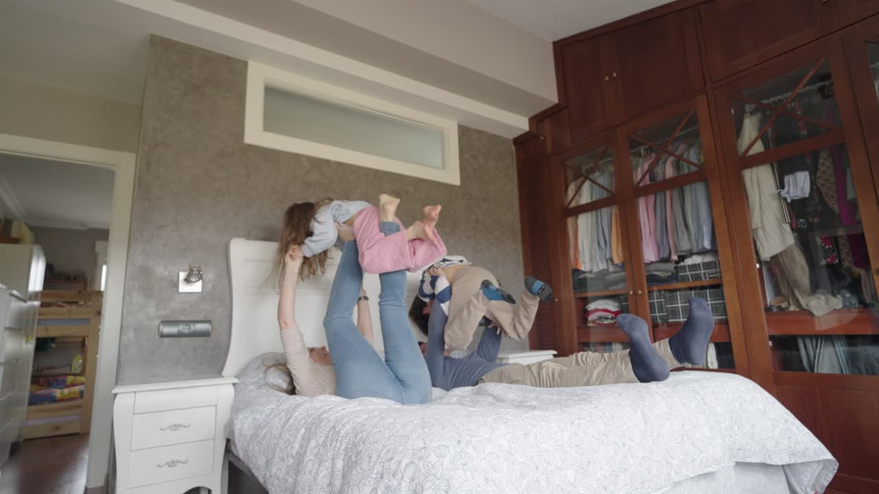 Family playing with children on a bed in a bedroom