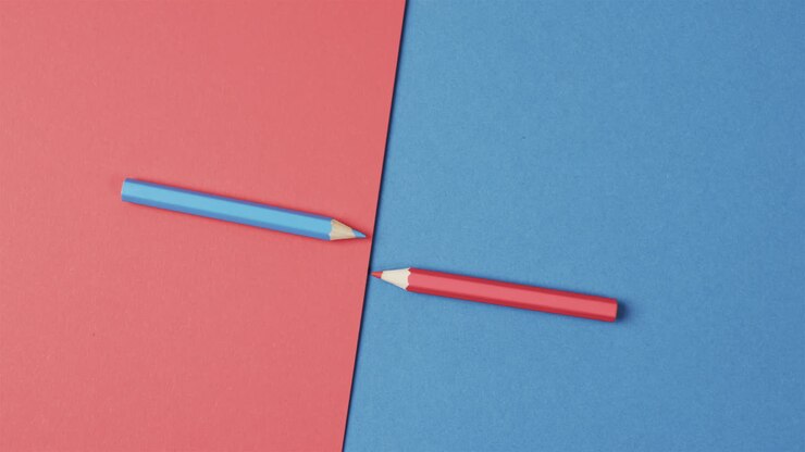 Overhead view of blue and red crayons arranged on red and blue background, in slow motion