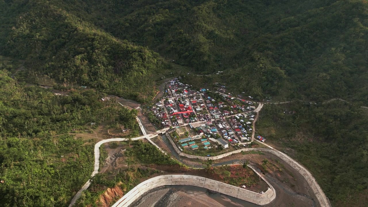 Cảnh quay lùi từ trên cao những con đường quanh co dẫn đến ngôi làng barangay cổ kính giữa những ngọn núi thung lũng tươi tốt - Obi, Caramoran, Catanduanes, Philippines