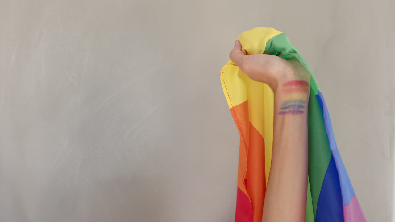 Holding rainbow flag, person with pride colors painted on arm