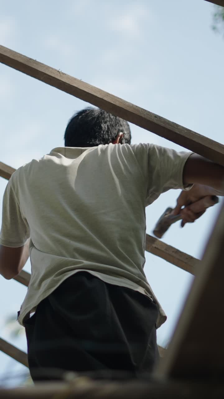 Man working on a wooden structure under a clear sky