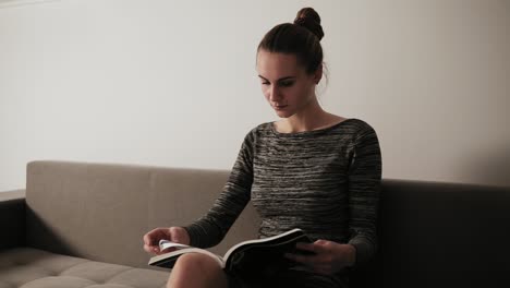 portrait of a young attractive woman reading a magazine while sitting on the couch in her living room. leisure time