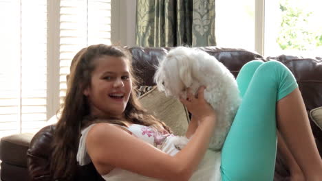 little girl sitting on couch playing with puppy