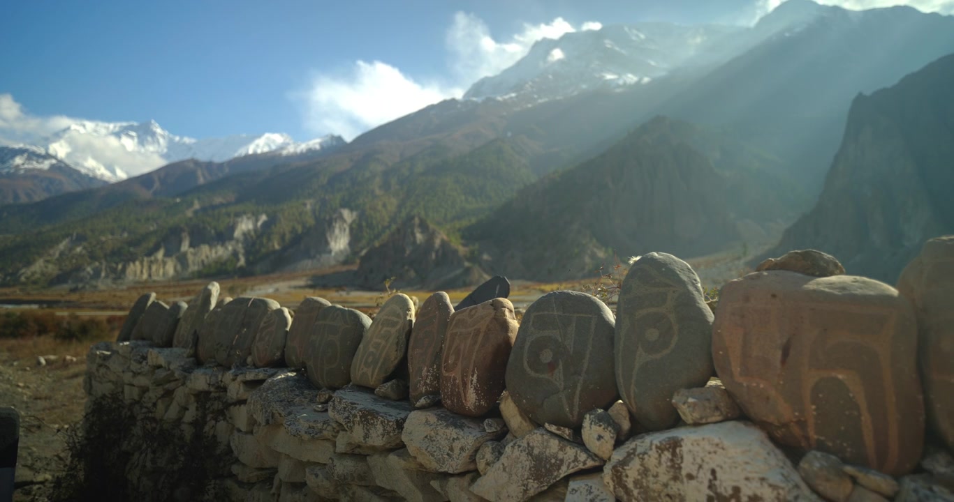 Circuito dell'Annapurna, Manang Nepal, muro sacro di pietre mani scolpito con mantra di fronte a un suggestivo paesaggio montano himalayano
