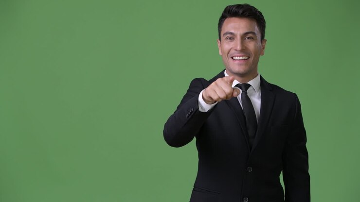 Young handsome Hispanic businessman against green background