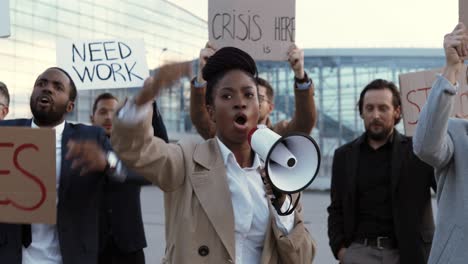 african american woman talking on loudspeaker with arms up in a protest with multiethnic business colleagues in the street