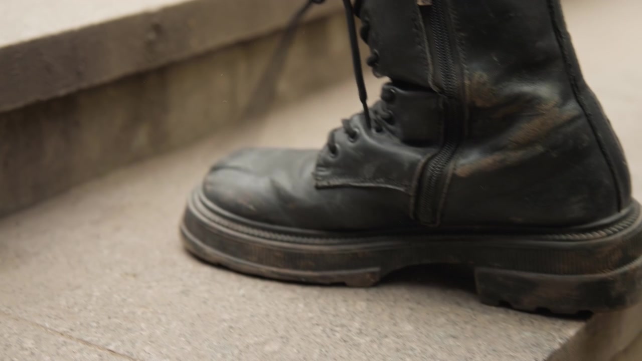 Nabije patrouille stopt wanneer de laars de grond raakt. Schoenen stevig geplaatst op een stoeprand tijdens een stadspatrouillepauze. Gedetailleerd beeld van laarszool en teen terwijl een patrouilleofficier pauzeert tijdens stedelijke surveillance.