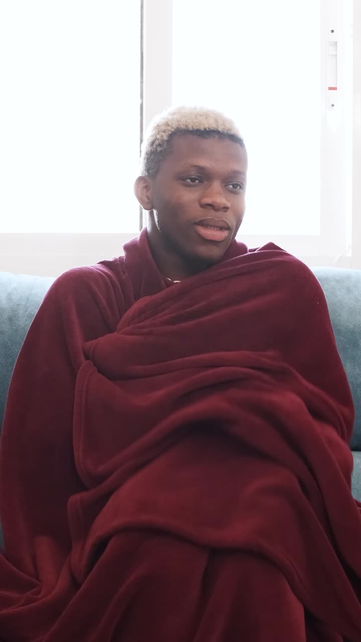 Young Man Resting on a Couch Wrapped in a Blanket