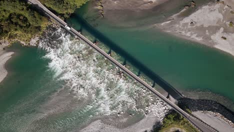 Autocaravana-Cruzando-Un-Puente-Angosto-Sobre-Agua-De-Deshielo-Glacial-De-Colores-Vibrantes