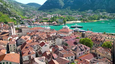 drone passing forward above city center of kotor. famous travel destination in montenegro. luxury yachts and boats. turquoise water.