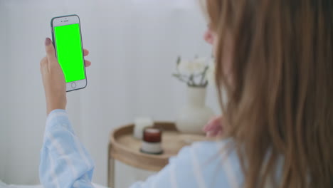 hermosa mujer usando pantalla táctil de teléfono inteligente en una habitación luminosa. joven mujer morena atractiva habla a través de una videollamada en la cámara web del teléfono inteligente con un amigo en el dormitorio por la mañana