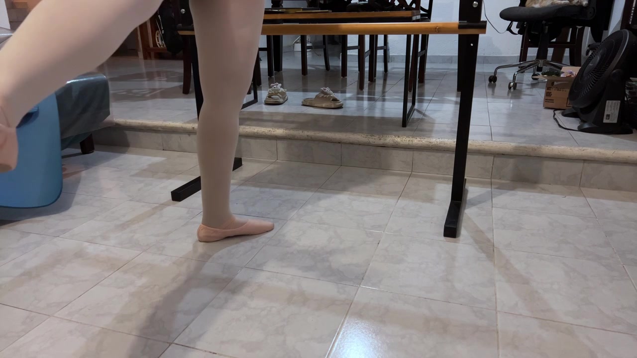 Ballet dancer practices graceful movements indoors with natural lighting and tiled flooring